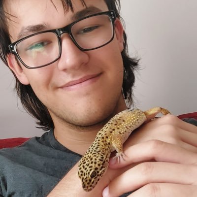 A picture of Toby Rodel wearing glasses with a small yellow and black spotted lizard on their arm